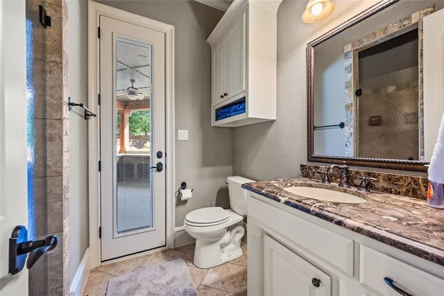 a bathroom with a granite countertop toilet a sink and a mirror