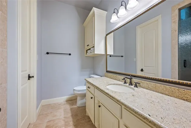 a bathroom with a granite countertop sink a toilet and a mirror