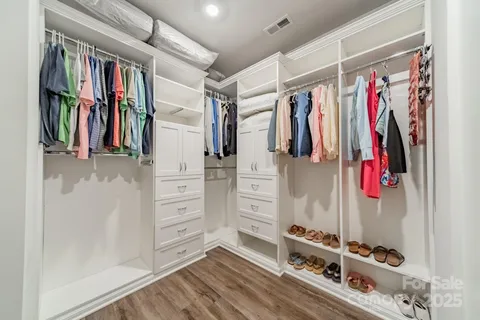 a view of walk in closet with clothes and shoes