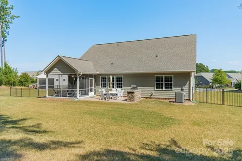a view of house that has a big yard with table and chairs a barbeque with wooden fence