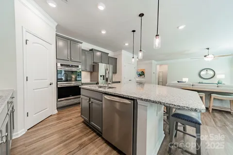 a kitchen with stainless steel appliances granite countertop a sink a stove and a refrigerator