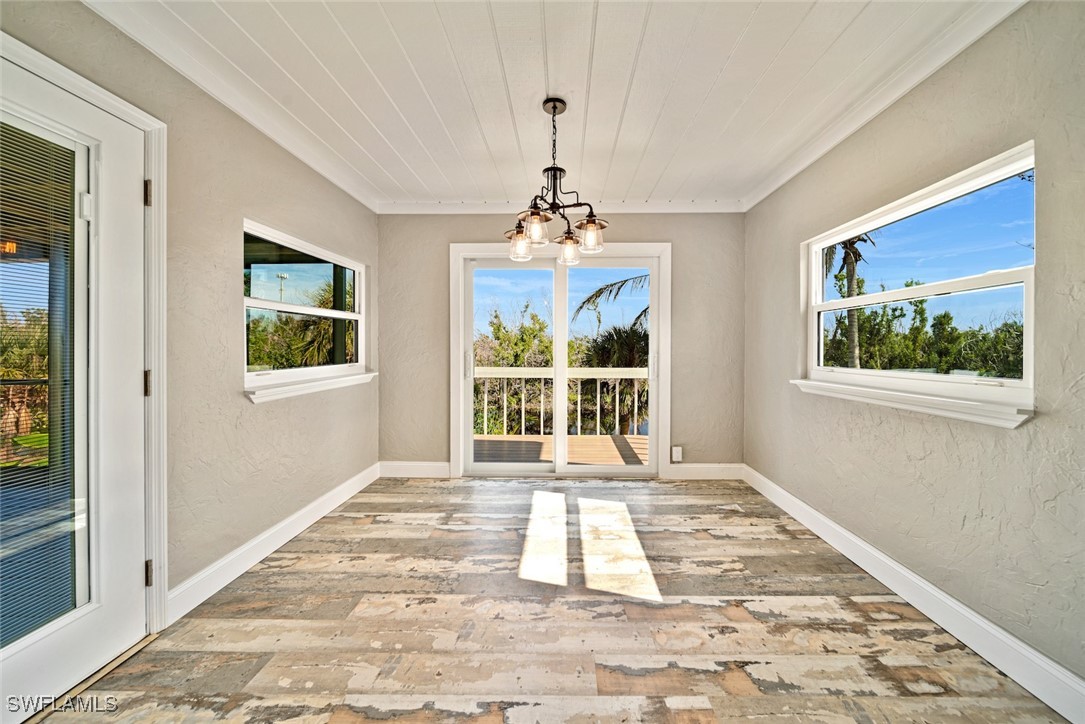 812 Rabbit Road Sanibel, FL 33957 - Photo 8 of 49 a view of a room with wooden floor a chandelier and windows