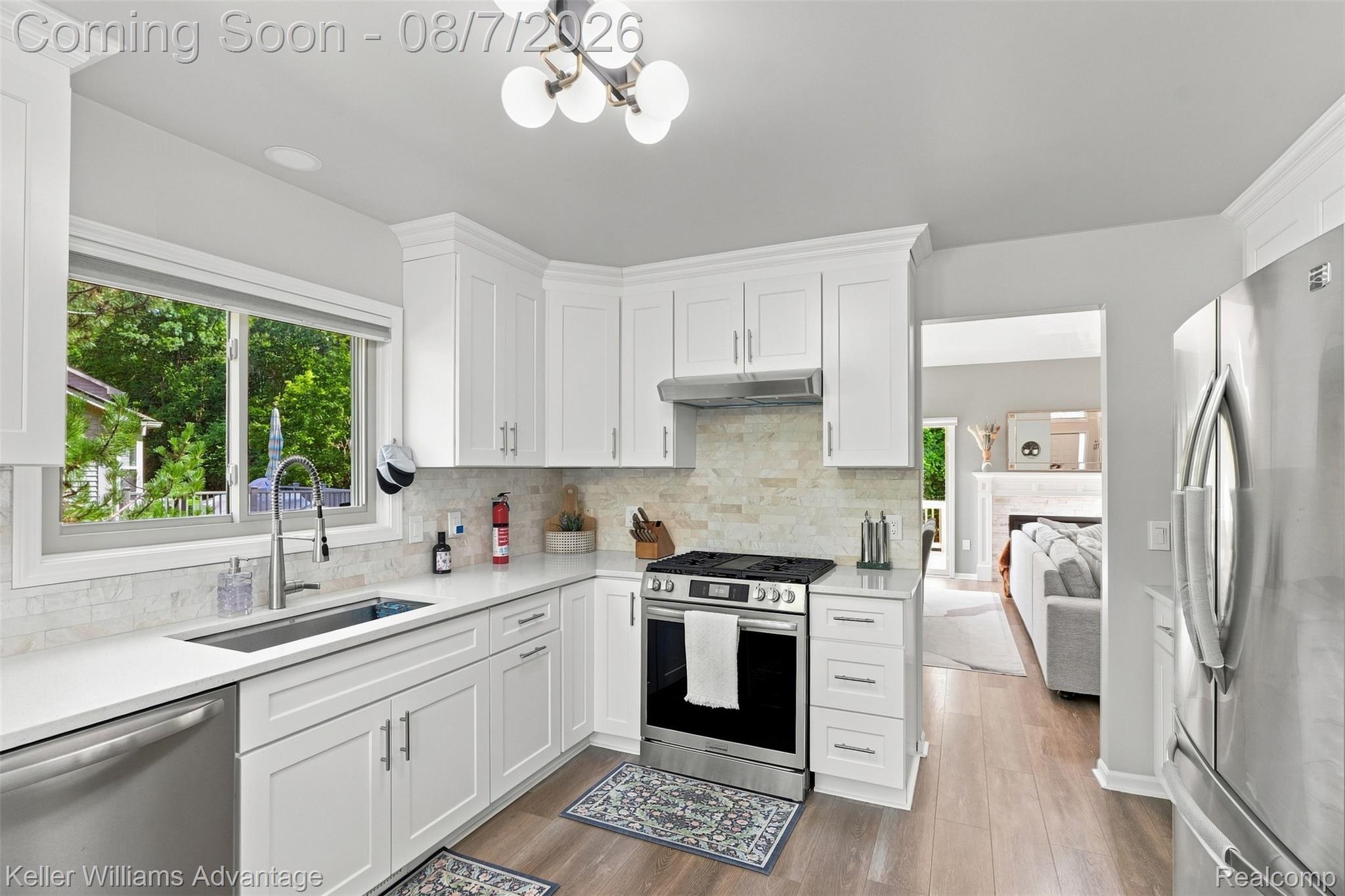 5325 Simpson Lake Road West Bloomfield, MI 48323 - Photo 13 of 43 White shaker cabinetry, stainless steel appliances, light-toned countertop, tile backsplash, and wood-finish flooring