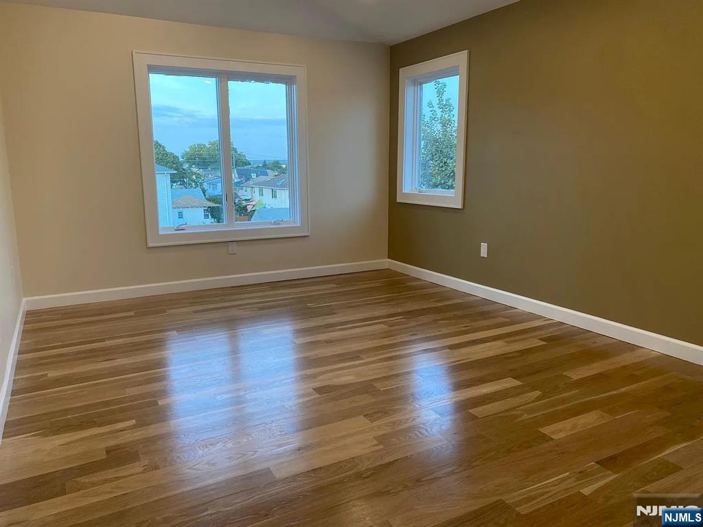 353 Hoboken Road Carlstadt, NJ 07072 - Photo 3 of 12 a view of an empty room with wooden floor and a window
