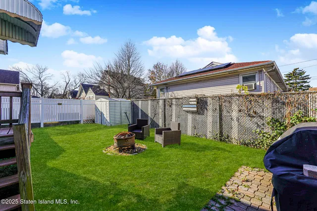 a view of backyard with barbeque grill potted plants and large tree