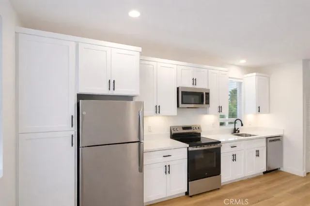 a kitchen with stainless steel appliances a refrigerator sink and white cabinets