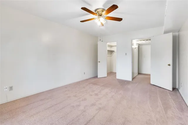 an empty room with closet and a ceiling fan