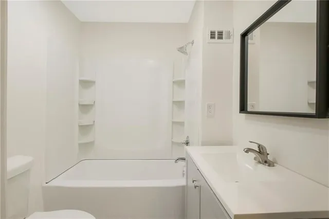 a white bath tub sitting next to a white sink and vanity