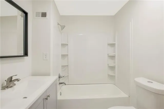 a bathroom with a bathtub shower sink vanity and toilet