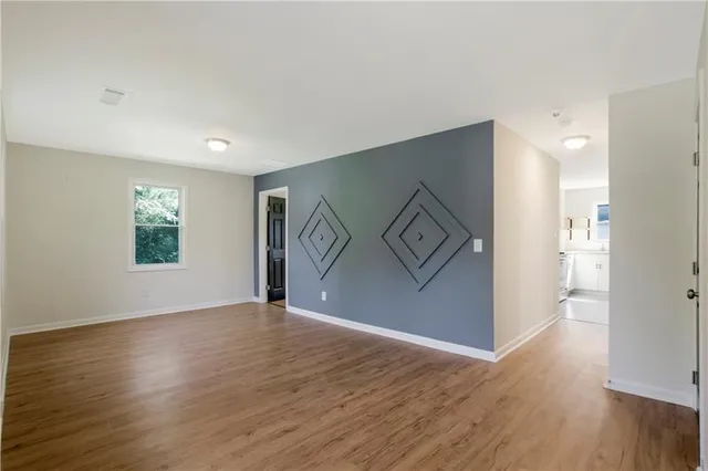 a view of an empty room with wooden floor and a window