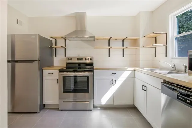 a kitchen with stainless steel appliances a stove a sink and a refrigerator