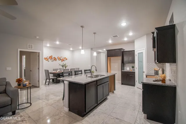 a kitchen with stainless steel appliances kitchen island granite countertop a sink and a refrigerator
