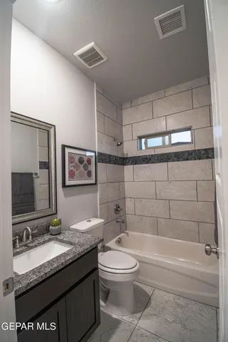 a bathroom with a granite countertop toilet sink and mirror