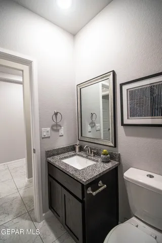 a bathroom with a granite countertop sink and a toilet