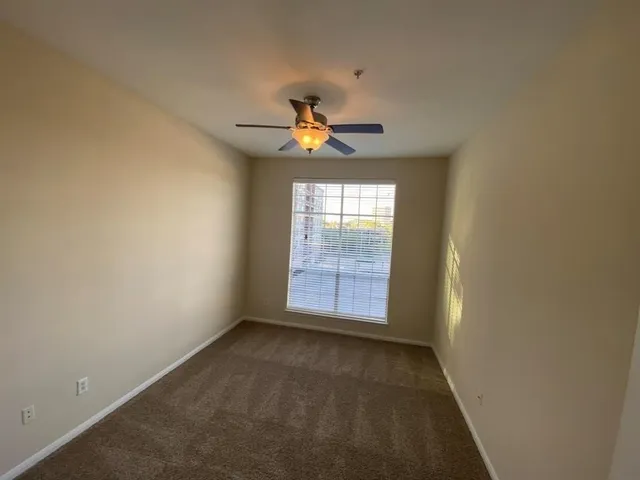an empty room with a window and a fan