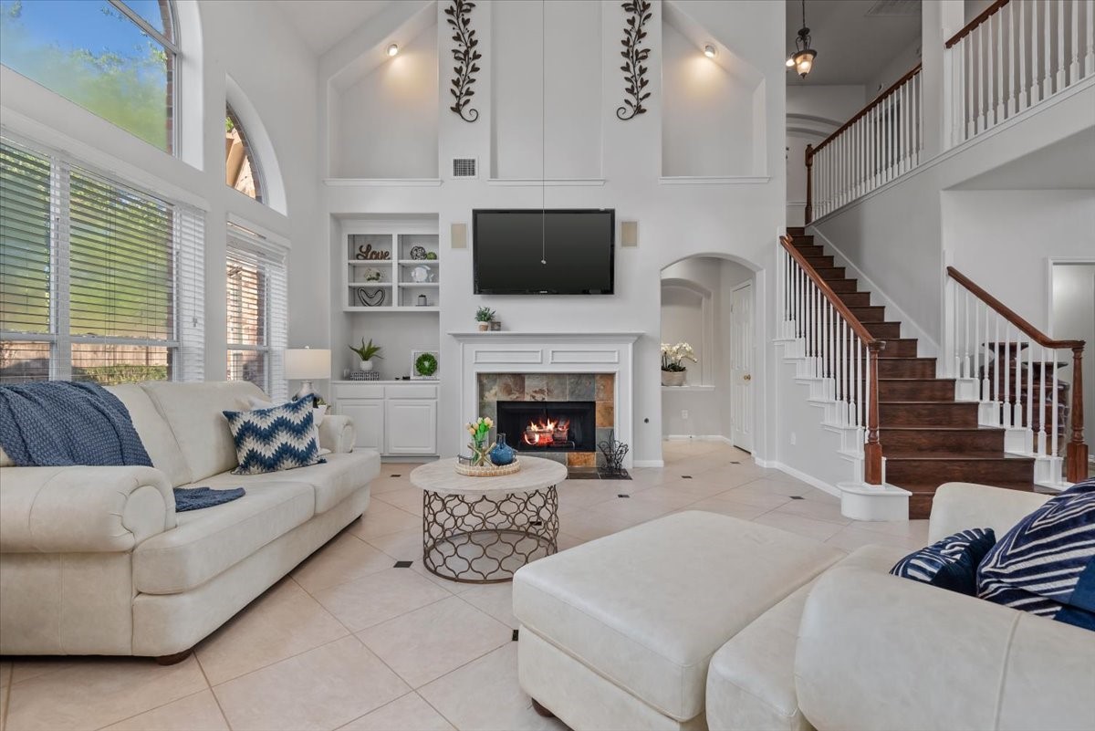 6507 Quiet Pointe Drive Spring, TX 77389 - Photo 3 of 46 This spacious living room features high vaulted ceilings, a cozy fireplace, and large windows offering plenty of natural light. An open staircase leading to the upper level, creating a welcoming and stylish atmosphere.