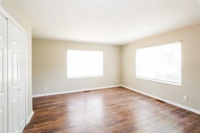 an empty room with wooden floor and windows