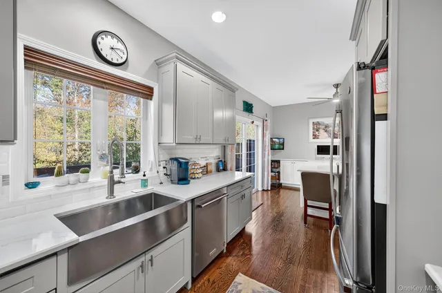 a kitchen with stainless steel appliances a refrigerator a stove a sink dishwasher and a dining table with wooden floor