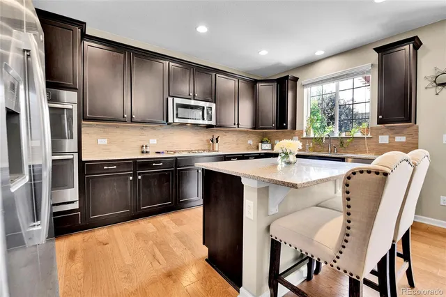 a kitchen with stainless steel appliances granite countertop a stove a sink a microwave a refrigerator and cabinets