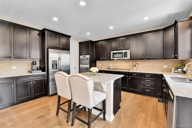 a kitchen with granite countertop wooden cabinets a stove a microwave a island with stainless steel appliances