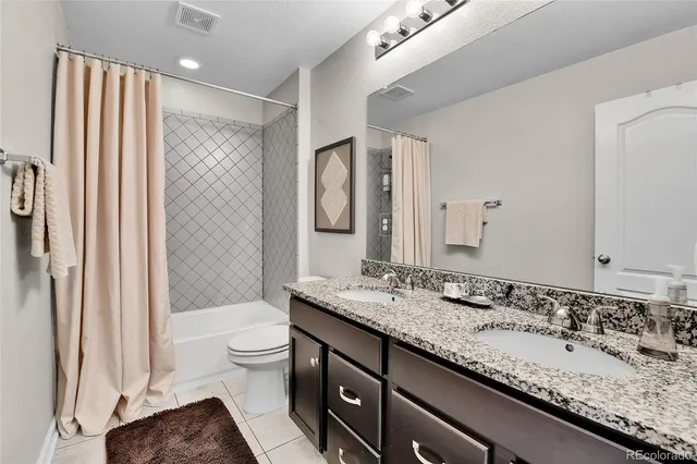 a bathroom with a granite countertop sink a toilet a mirror and shower