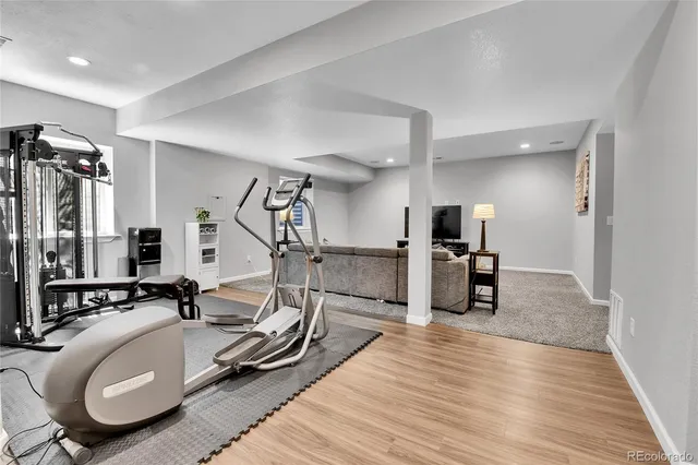 a room with gym equipment and wooden floor
