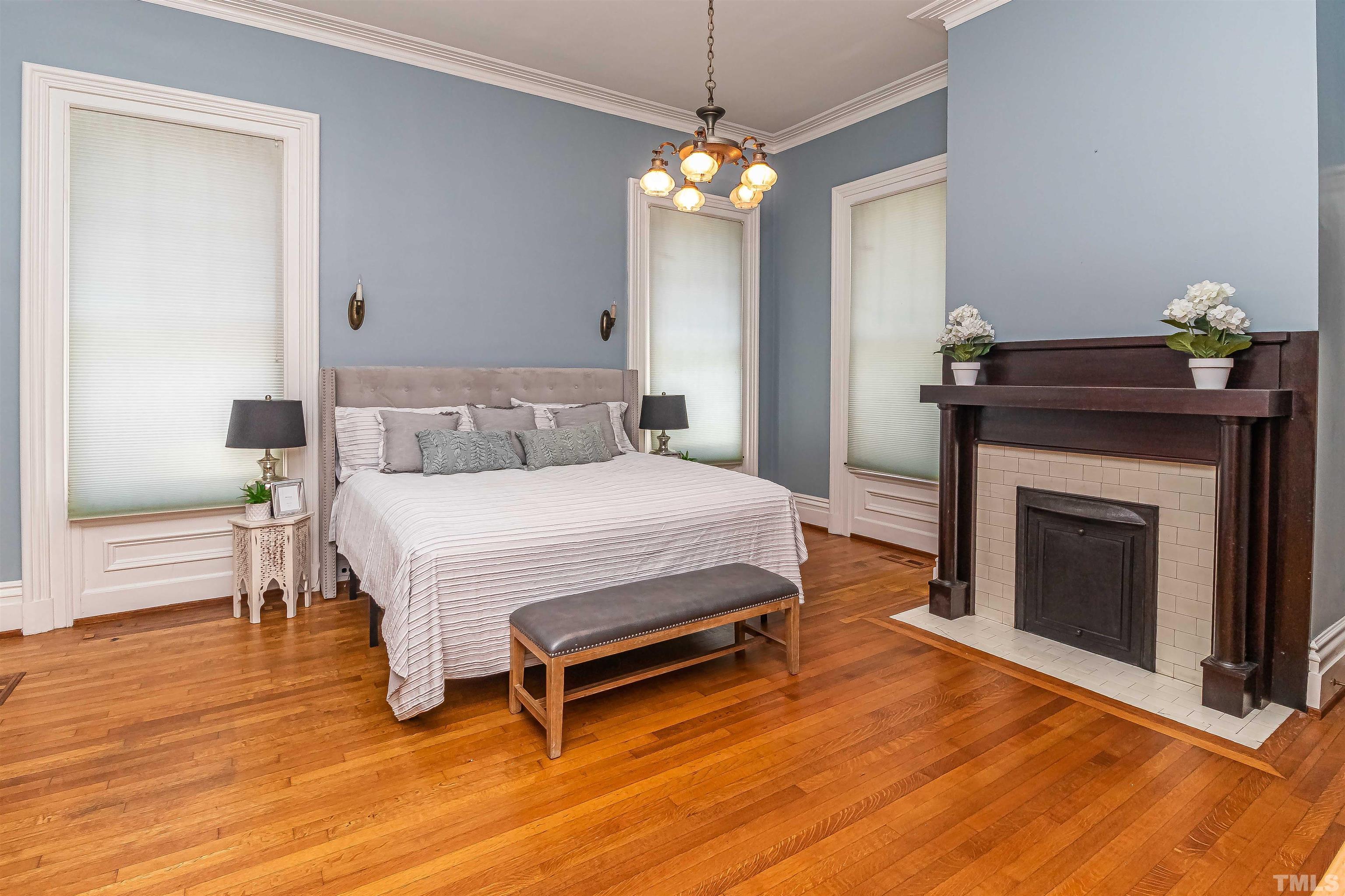111 South George Street Goldsboro, NC 27530 - Photo 8 of 51 a spacious bedroom with a bed and a chandelier