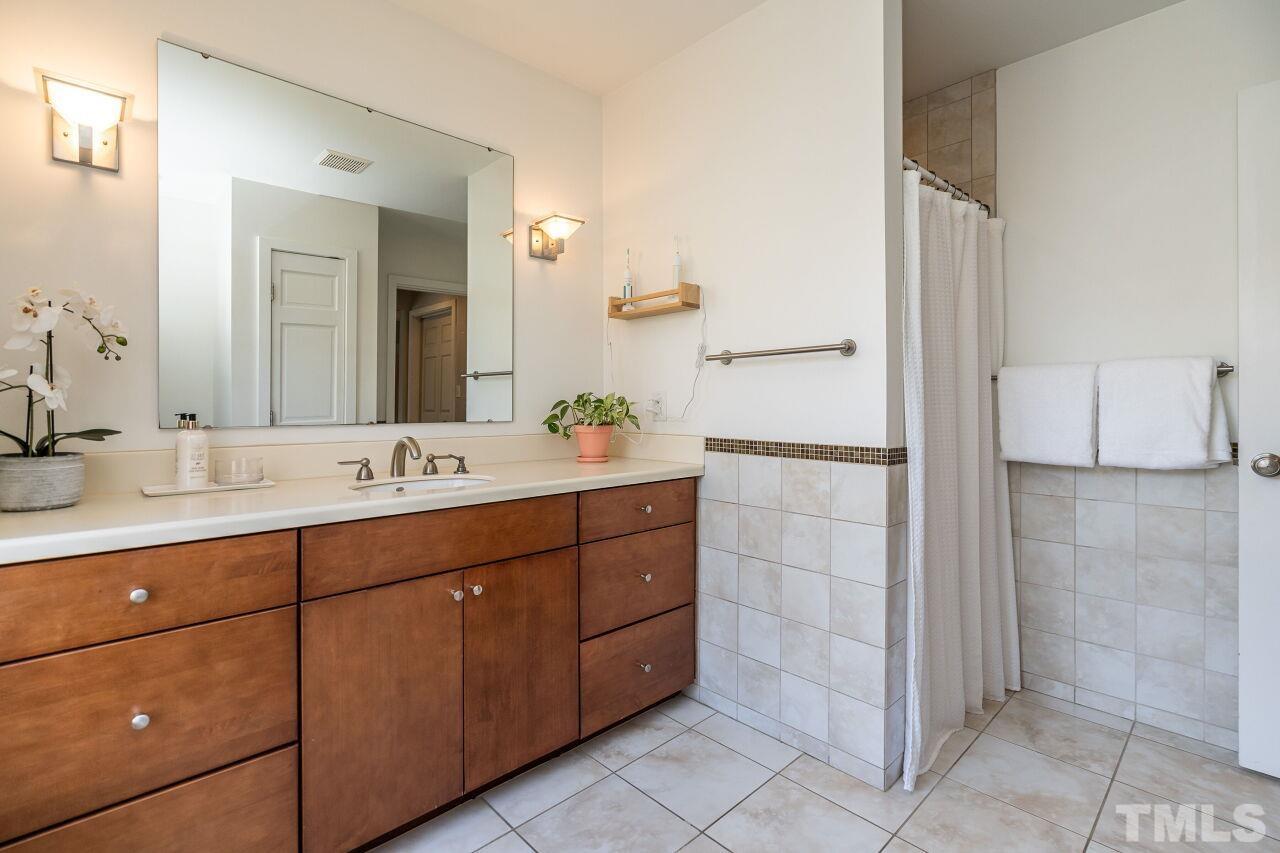 118 East Whitaker Mill Road Raleigh, NC 27608 - Photo 15 of 21 a bathroom with a double vanity sink a mirror and a shower