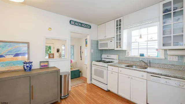 a kitchen with a sink stove cabinets and wooden floor