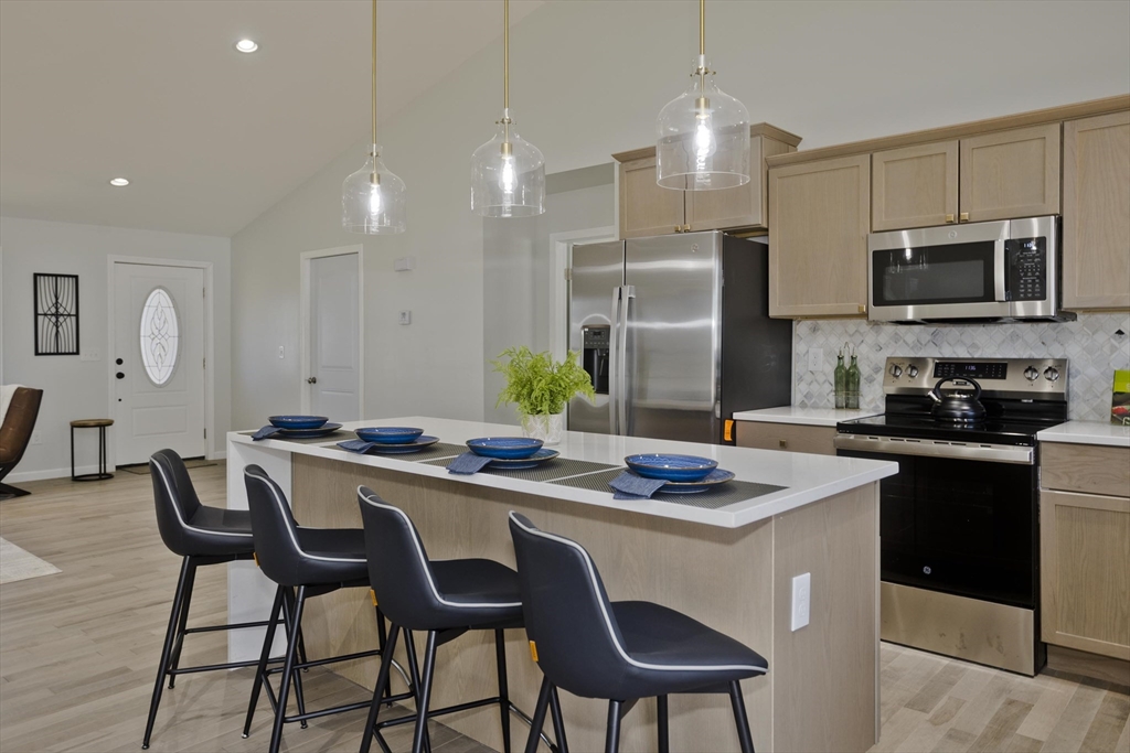 72 Lancaster Street Springfield, MA 01118 - Photo 7 of 35 a kitchen with stainless steel appliances granite countertop a stove a sink a microwave a island with a dining table and chairs