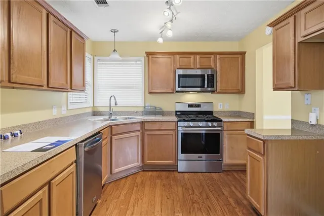 a kitchen with stainless steel appliances granite countertop a stove a sink and a microwave