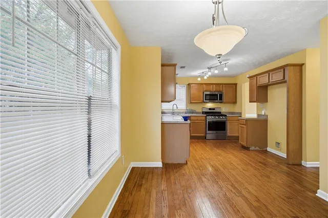 a kitchen with stainless steel appliances granite countertop a refrigerator a stove top oven a sink dishwasher and white cabinets with wooden floor