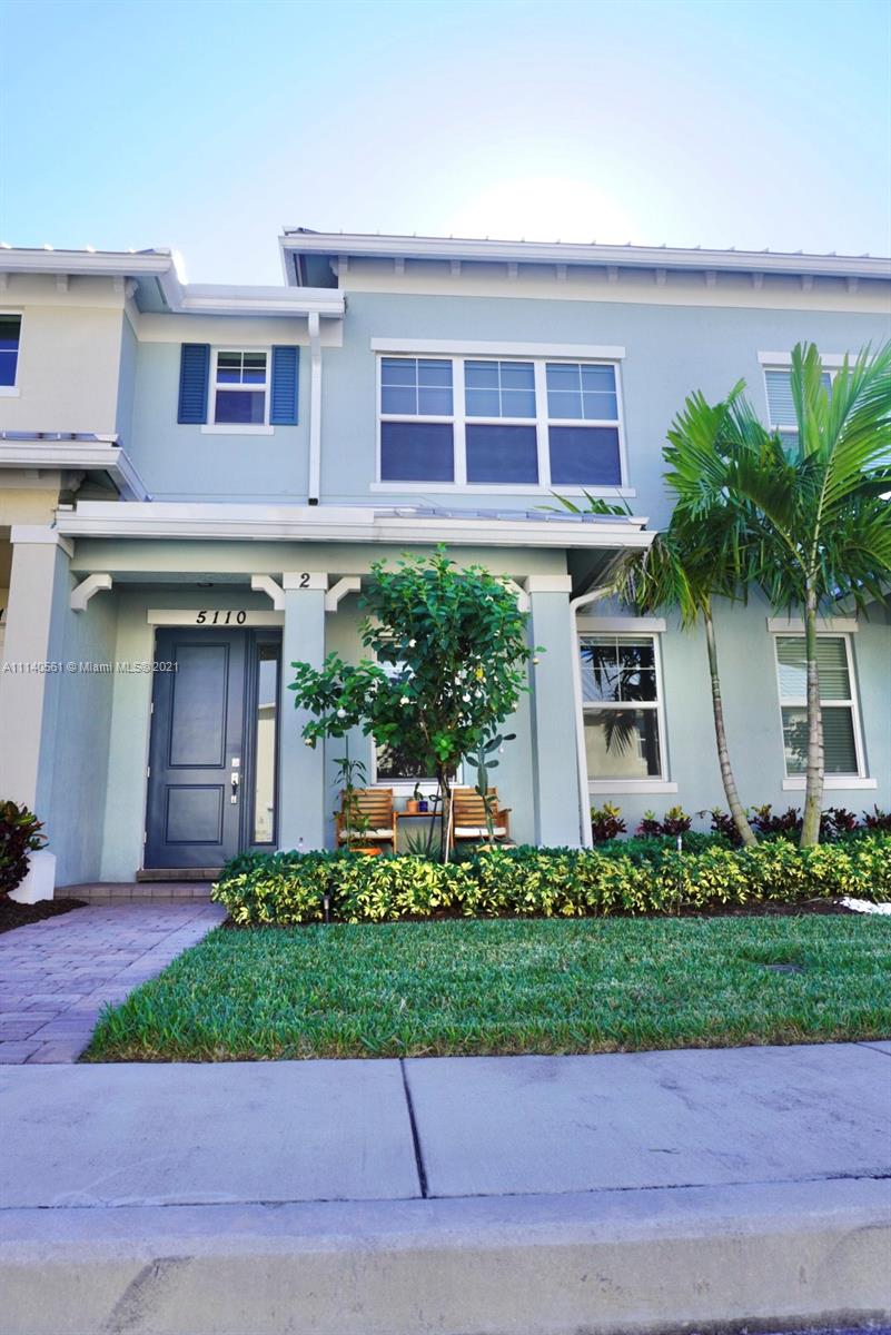 a front view of a house with a yard and potted plants