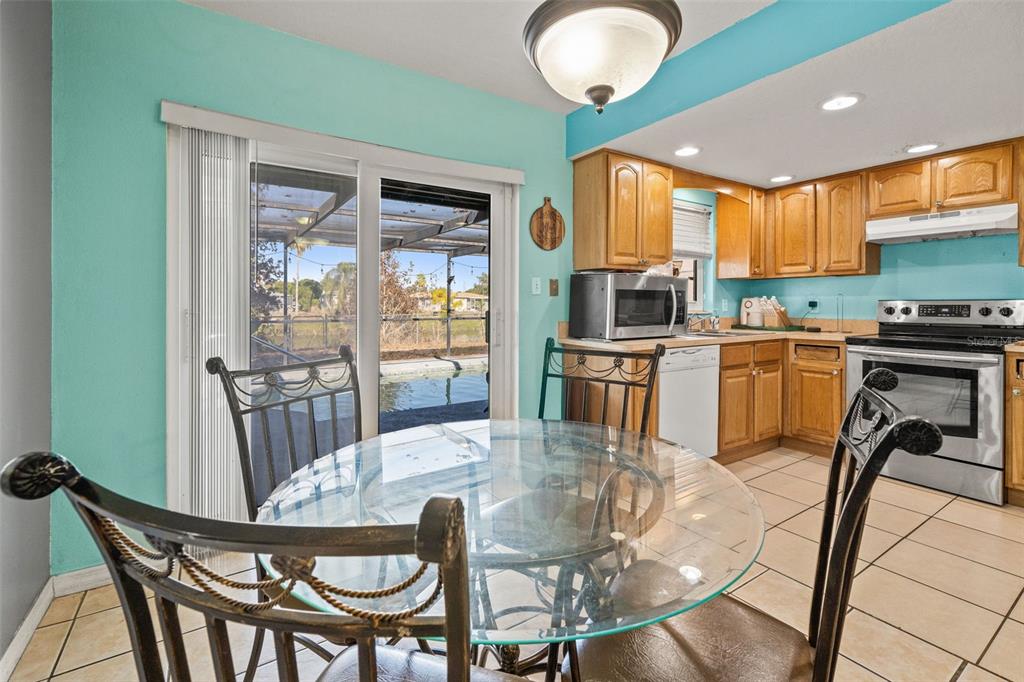 8025 Durham Drive Port Richey, FL 34668 - Photo 4 of 30 a kitchen with stainless steel appliances granite countertop a stove a refrigerator a kitchen island a table and chairs