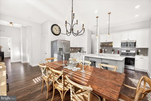 a kitchen with stainless steel appliances granite countertop a kitchen island a stove a table and chairs with wooden floor