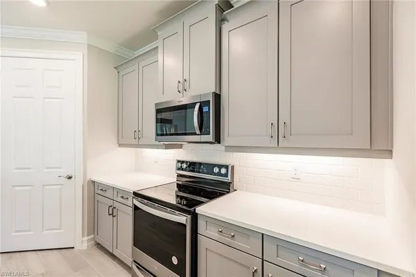 a kitchen with stainless steel appliances a sink a stove a refrigerator cabinets and a window