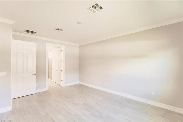 a view of a hallway with white cabinets and wooden floor