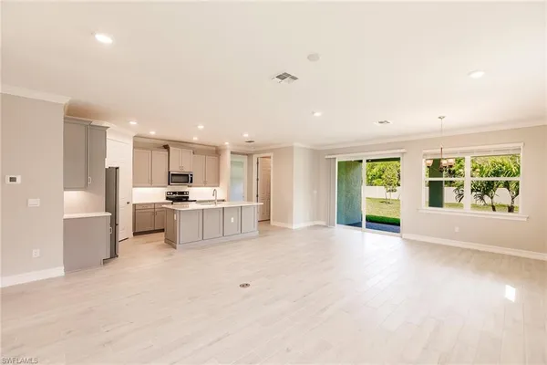 a large white kitchen with a large island oven a stove and white cabinets with wooden floor
