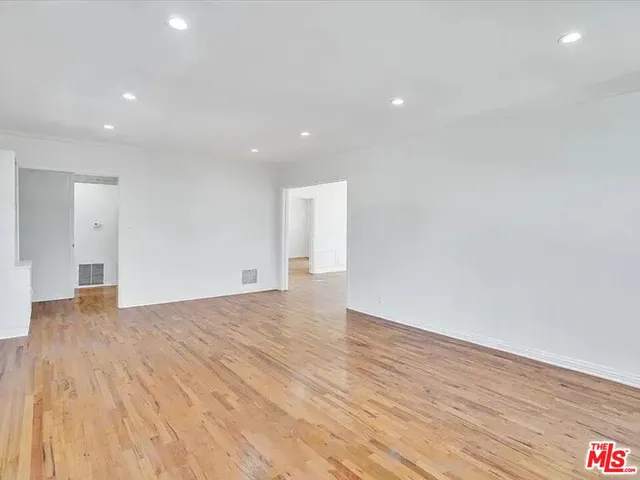 a view of an empty room with wooden floor and entryway