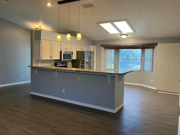 an open kitchen with wooden floor and large window