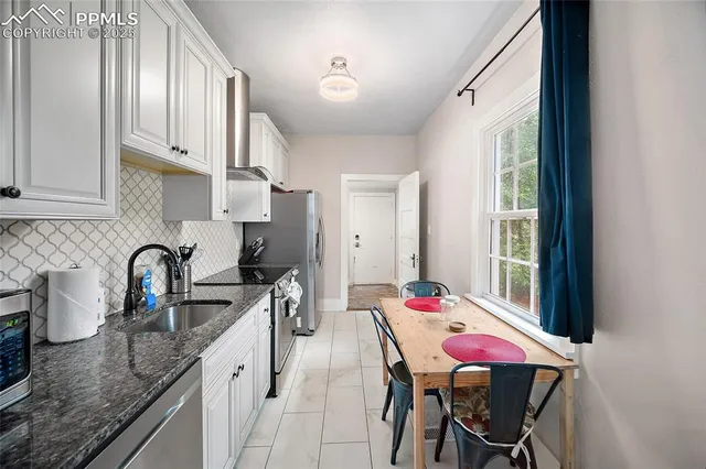 a kitchen with stainless steel appliances kitchen island a table chairs in it and wooden floors
