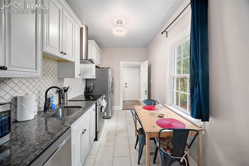225 Custer Avenue Colorado Springs, CO 80903 - Photo 12 of 39 a kitchen with stainless steel appliances kitchen island a table chairs in it and wooden floors