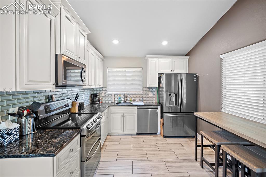 225 Custer Avenue Colorado Springs, CO 80903 - Photo 21 of 39 a kitchen with stainless steel appliances granite countertop a refrigerator a stove a sink a dining table and chairs