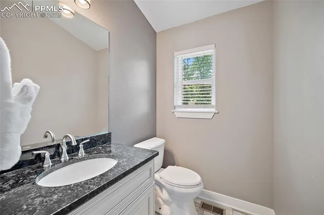 a bathroom with a granite countertop toilet a sink and a mirror