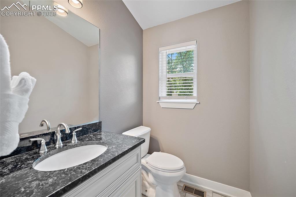 225 Custer Avenue Colorado Springs, CO 80903 - Photo 26 of 39 a bathroom with a granite countertop toilet a sink and a mirror