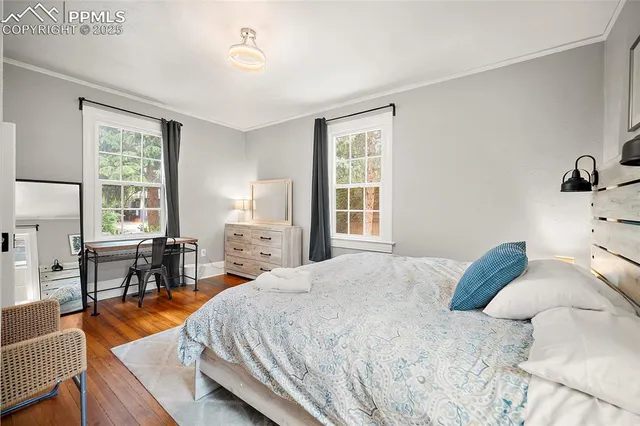 a bedroom with a bed and a table in it with wooden floor