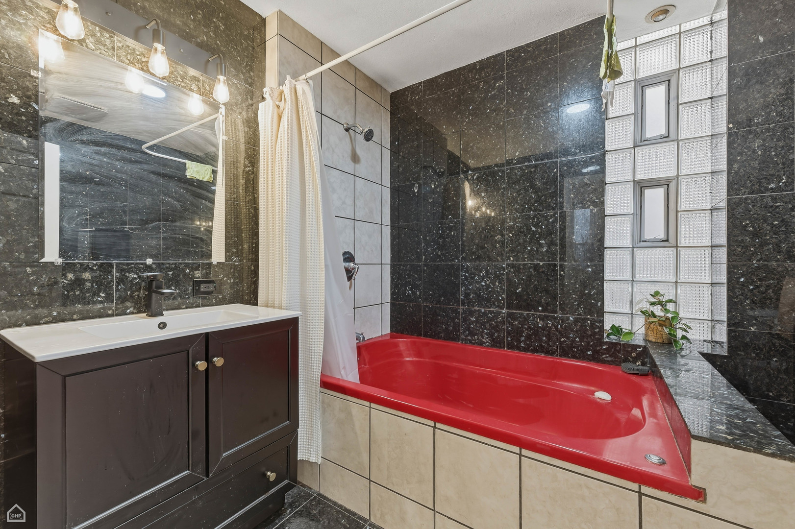 822 North Wood Street Chicago, IL 60622 - Photo 10 of 28 a bathroom with a granite countertop sink a mirror and a bathtub