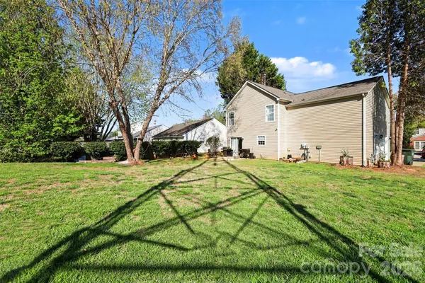 a view of a big yard with potted plants and large trees