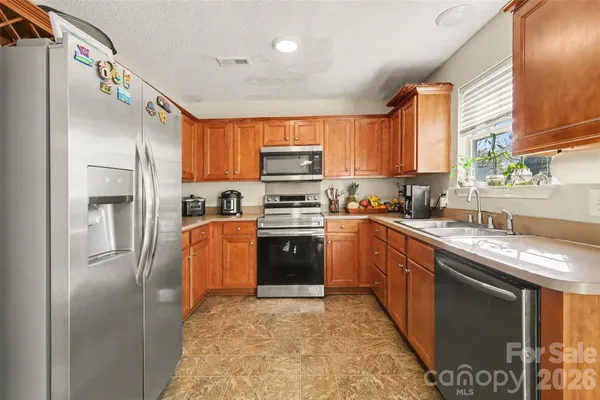 a kitchen with granite countertop a refrigerator stove top oven and sink