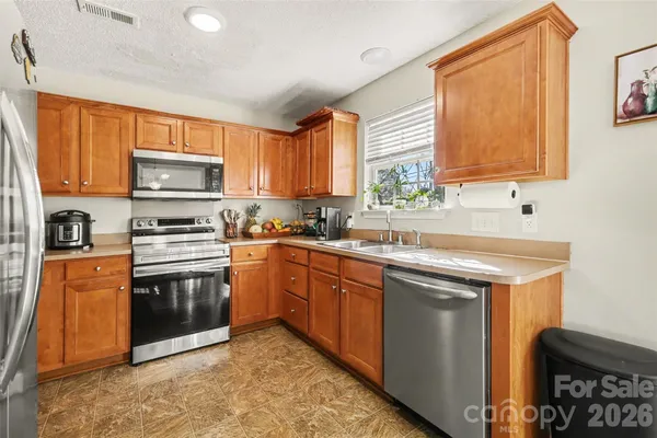 a kitchen with stainless steel appliances granite countertop a stove a sink and a microwave